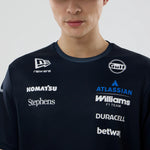 Person wearing a dark blue shirt with various brand logos on a light gray background