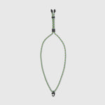 Green and black braided dog leash on a light gray background