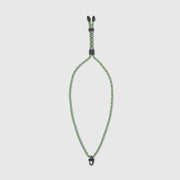 Green and black braided dog leash on a light gray background