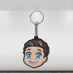 A colorful caricature keyring featuring a smiling cartoon character with blue eyes and a Mercedes-Benz logo on the keyring.