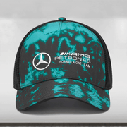 A multicolored tie-dye trucker cap with a Mercedes-AMG Petronas Formula One Team logo on the front, mesh back panels, and an adjustable snapback closure.
